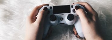 Weibliche Hände mit lackierten Fingernägeln halten einen PlayStation-Controller.